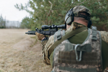 Fototapeta premium Soldier Aiming with Scoped Rifle in Natural Landscape
