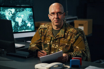 Portrait of military officer wearing uniform in command center holding documents. Command center...