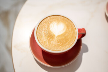 Coffee in pink cup on white table in café 