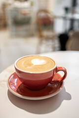 Coffee in pink cup on white table in café 