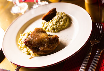 Dish duck leg with green perlotto served on a white plate