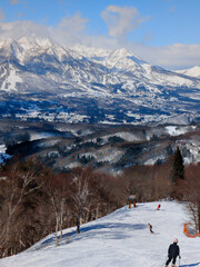 Skiers on ski slope with spectacular mountains in Nagano, Japan