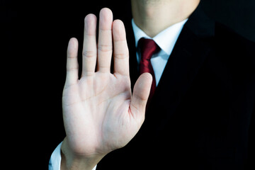 A man in a suit holds his hand up in a 