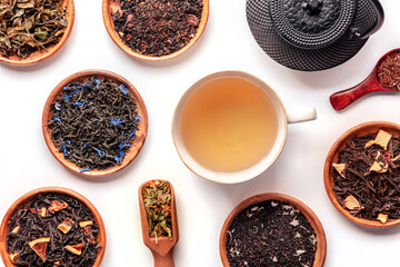 Loose tea leaves. An assortment of herbal, floral, and fruit teas and infusions, with a tea cup, overhead flat lay shot with a cup, on a white background