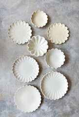 A selection of handmade stoneware ceramics in various glazes and decorations on warm stone background 