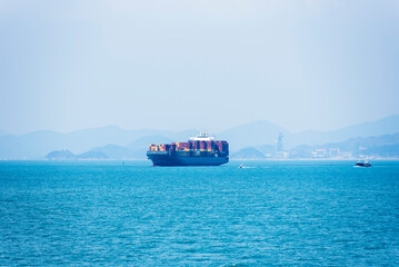 Cargo container ship sailing along of South Korean coast on her way out from container terminal in...