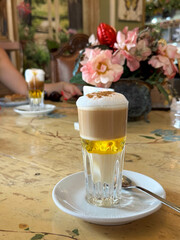 Traditional Canary Islands Barraquito Coffee on a table in cafe with flowers on the background