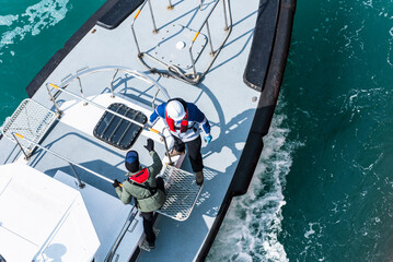 Aerial, top view on the pilot boat - pilot preparing to enter cargo ship using gangway, he will...