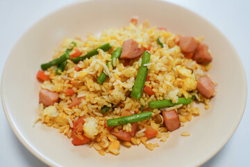 Fried rice with egg, carrots and ham sausage. A plate of special fried rice. Staple food in China..