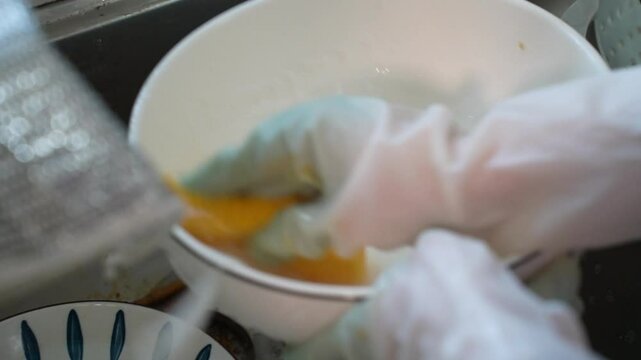 wash plate in kitchen sink. dish cleaning. manually washing white plate. washing dish. kitchenware work. housework after dinner.