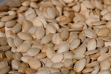 Pumpkin seeds spread out in natural light showcasing their unique shapes and textures