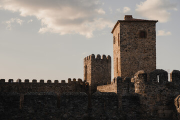 Muralla medieval con torre de piedra en un día soleado.