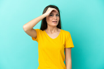 Young caucasian woman isolated on blue background doing surprise gesture while looking front