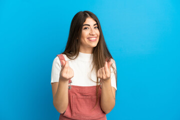 Fototapeta premium Young caucasian woman isolated on blue background making money gesture