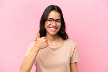 Young Colombian woman isolated on pink background With glasses and with thumb up