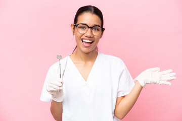 Dentist Colombian woman isolated on pink background extending hands to the side for inviting to come