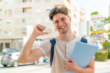 Young handsome student man at outdoors proud and self-satisfied