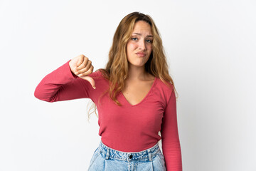 Young blonde woman isolated on blue background showing thumb down with negative expression