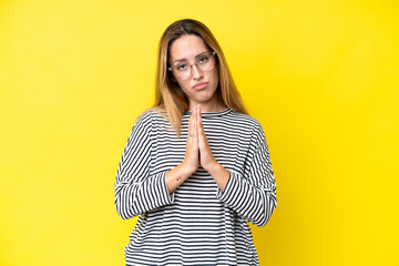 Young caucasian woman isolated on yellow background keeps palm together. Person asks for something