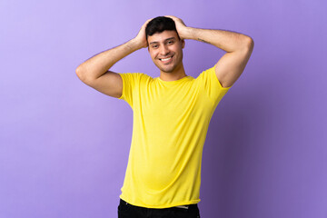 Young Colombian man isolated on purple background laughing