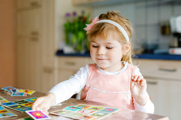 Adorable cute toddler girl playing picture card game. Happy healthy child training memory,...