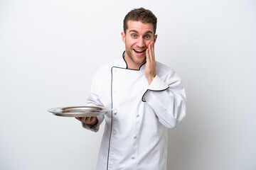 Young caucasian chef with tray isolated on white background with surprise and shocked facial...
