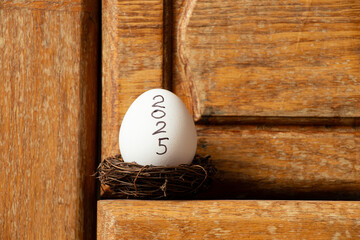 Chicken eggs in a nest with the inscription 2025 on a wooden shelf in the kitchen, egg shortage