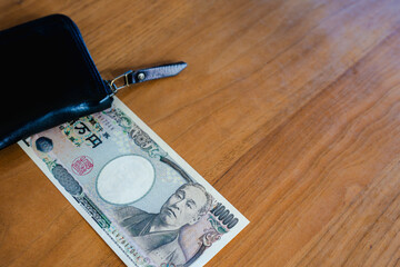 旧一万円札と黒い財布、家計管理のイメージ