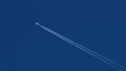 The journey begins, plane flies high in the blue sky, leaving a white trail. Jet airplane flying overhead in clear blue sky and leaving nice contrail. Plane smoothly as it flies through the sky