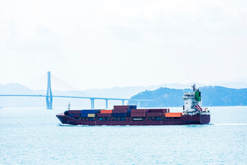 Cargo container ship sailing along of South Korean coast on her way out from container terminal in Busan New Port.
