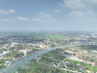 The River's Embrace: An Aerial Glimpse of little town Urban Heart. This drone photograph captures a wide aerial view of Nakhon Pathom, Thailand, with a focus on the river that flows through town