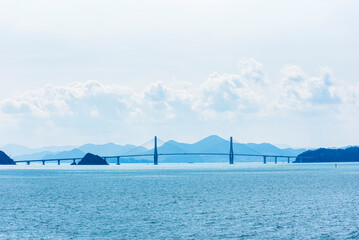 South Korea, costal landscape with bridge near the entrance to the sea port and container terminal in Busan New Port.