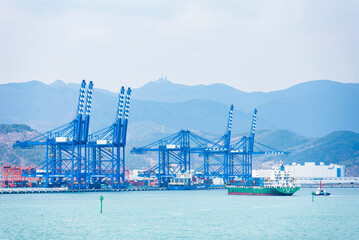 Container terminal of New Port in Busan, landscape with gantry cranes and cargo ship.