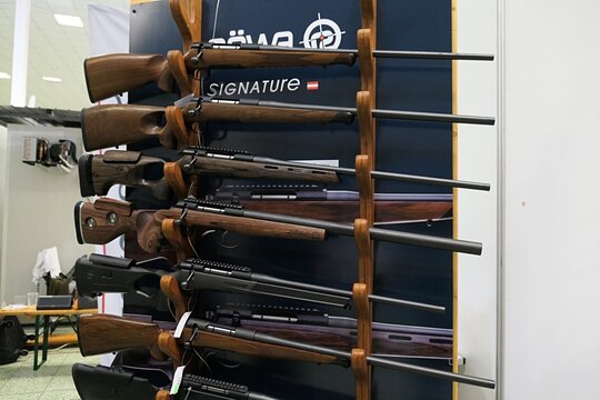 Advertising wooden hunting rifle rack of austrian manufacturer Rossler Rowa (with Signature and Titan 6 models present), based in Kufstein, displayed on slovak Hunting Expo in Nitra, march 2025.