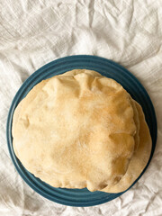 Stack of freshly baked pita bread on a blue ceramic plate.