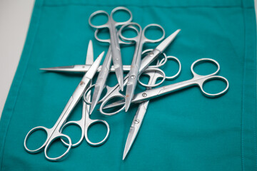 Surgical scissors gathered on a green cloth.