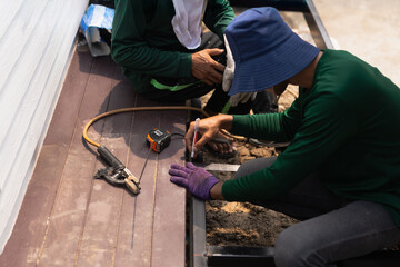 Two builder measures the length of a metal profile with a ruler measure.