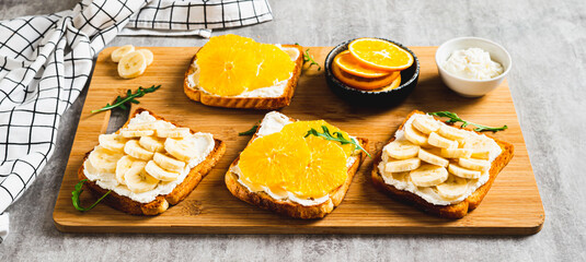 Crispy sandwiches with cottage cheese and fruits on a board on a table web banner