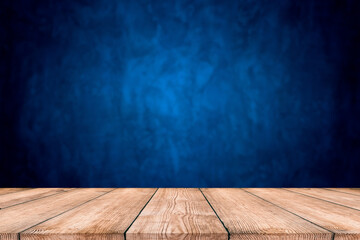 Dark blue background, with empty wooden table, dark wall background. Empty workplace in front of abstract package.
