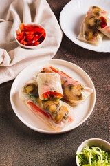 Delicious spring rolls with vegetables and mushrooms in rice paper on a plate vertical view