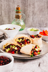 Salad of beans, cucumber and pepper in lavash rolls on a plate on the table vertical view