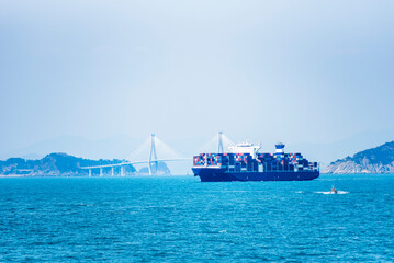 Cargo container ship sailing along of South Korean coast on her way out from container terminal in...