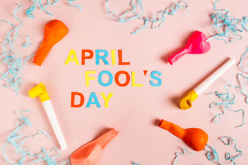 April Fools' Day made of colored letters, whistles, balloons and paper on pink top view