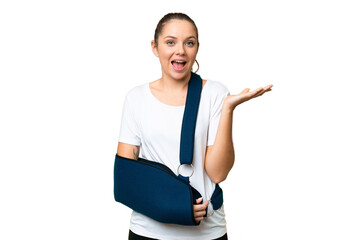 Young blonde woman with broken arm and wearing a sling over isolated chroma key background with...
