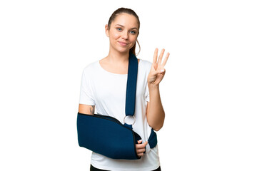 Young blonde woman with broken arm and wearing a sling over isolated chroma key background happy...