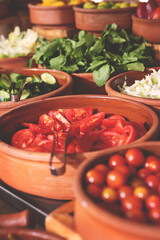Delicious buffet table with Fresh and Vibrant Organic Vegetables in Rustic Clay Bowls and greens, featuring variety of healthy and colorful plant-based dishes for vegetarian or vegan meal