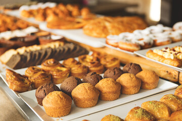 Close-up variety of freshly baked pastries, muffins and sweet rolls displayed on buffet table in cozy bakery or cafe setting for Breakfast, Brunch and Dessert Lovers Savoring Sweet and Savory Treats