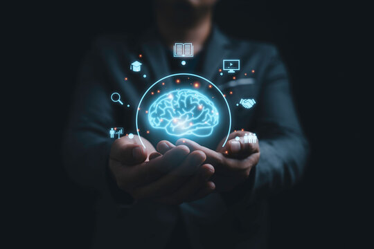 Businessman holding virtual glowing Brain with knowledge icons for study concept.