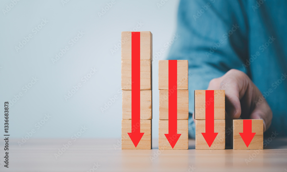 Poster businessman holding red down arrow which print screen on wooden block cube and copy space for cost p