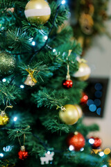 Golden shiny balls and bells hang on the branches of the Christmas tree